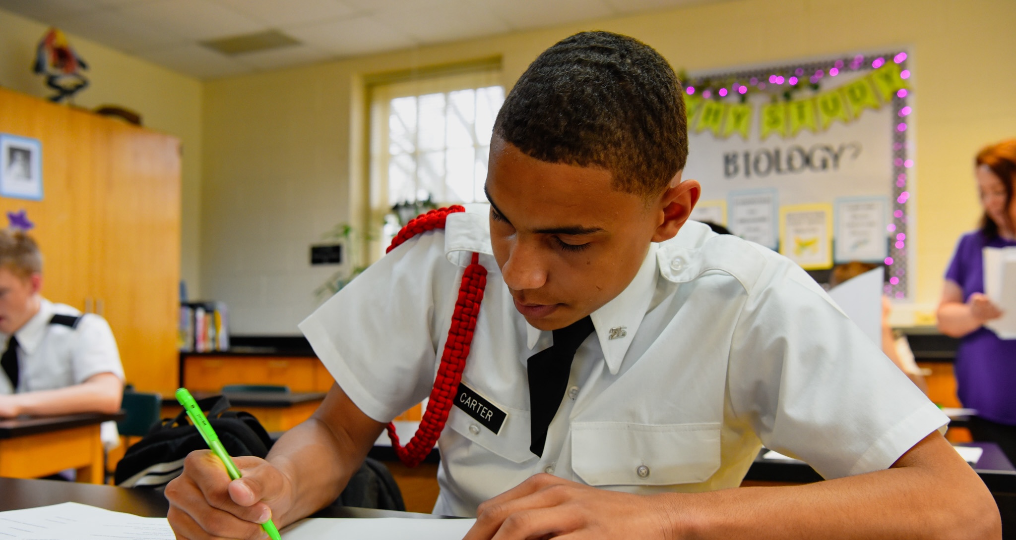 A Hargrave cadet in dress whites concentrating on written work at his desk